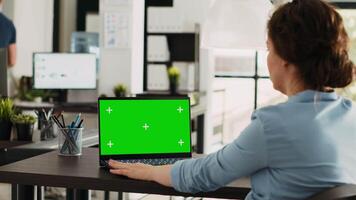 gerente trabajando a oficina escritorio con pantalla verde en computadora portátil, analizando Bosquejo chromakey monitor y aislado copyspace modelo. mujer utilizando personal computadora a puesto de trabajo. video
