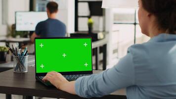 bedrijf persoon gebruik makend van Chroma sleutel laptop met groene scherm sjabloon in opstarten kantoor. bedrijf werknemer op zoek Bij mockup copyspace met geïsoleerd mockup Aan draadloze computer scherm. video