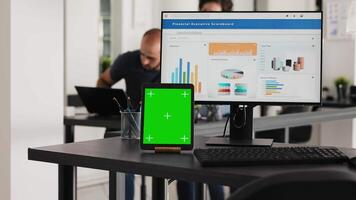 leeg bureau met groene scherm tablet en computer rennen operationeel gegevens, coworking ruimte voor bedrijf taken. computer bureaublad Bij werkstation met blanco Chroma sleutel mockup software Aan apparaatje. video