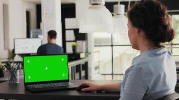 Manager working with greenscreen on laptop, checking isolated mockup template in creative agency office. Young adult looking at pc showing blank chromakey layout on display, modern software. video