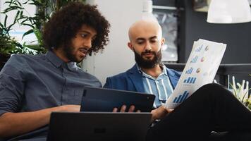 Startup team verify sales report with archived documents and information on laptop, comparing data to create briefing presentation. Coworkers discussing small business development strategy. photo