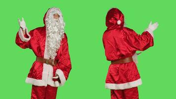 Santa claus cosplay shows advertisement, pointing aside while he poses against greenscreen backdrop with saint nick seasonal costume. Person dressed like father christmas, winter holiday marketing. photo