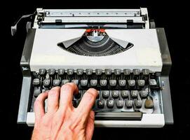 a person's hand is typing on an old typewriter photo