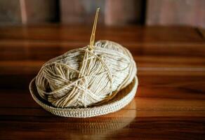 A yarn with a knitting needle stuck in it lies on a wooden table,Hobby crafts with yarn,hand made. photo