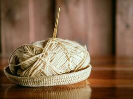 A yarn with a knitting needle stuck in it lies on a wooden table,Hobby crafts with yarn,hand made. photo