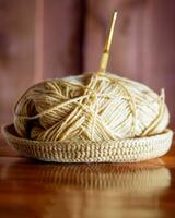 A yarn with a knitting needle stuck in it lies on a wooden table, Hobby crafts with yarn, hand made. photo