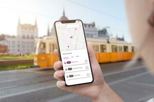 Trolleybus city transport app on smart phone in woman hand. Trolleybus in city in background photo