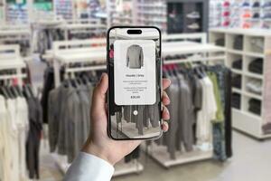 futuro de compras concepto en ropa tienda con un inteligente aplicación explorar prenda caracteristicas por simplemente señalando teléfono foto