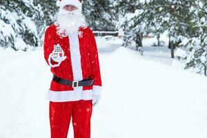 llave de la casa con llavero cabaña en manos de santa claus al aire libre en la nieve. trato de bienes raíces, compra, construcción, reubicación, hipoteca. hogar acogedor. feliz navidad, evento de reserva de año nuevo y sala foto