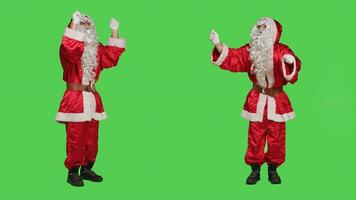 Santa choirmaster conducting band, conductor in winter seasonal costume accompany choir over full body greenscreen backdrop. Character pretends to be musical director, musician in studio. photo