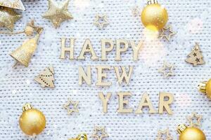 Happy New Year wooden letters on cozy festive white knitted background with sequins, stars, lights of garlands. Greetings, postcard. Calendar, cover photo