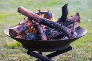 Metal fire bowl with burning wood in the yard. Safe decorative fire pit photo