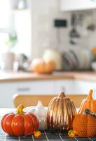 Decor of white classic kitchen with pumpkins, garlands, latern for Halloween and harvest with figurine of house. Autumn mood in home interior, modern loft style. real estate, insurance, mortgage photo