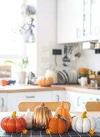 Decor of white classic kitchen with pumpkins, garlands, latern for Halloween and harvest with figurine of house. Autumn mood in home interior, modern loft style. real estate, insurance, mortgage photo