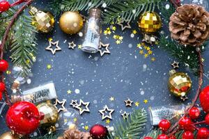Festive frame with a place for Christmas and New Year's theme text. Sequins, stars, garland, cones, balls on a black stone background of slate. Copyspace, greeting card photo