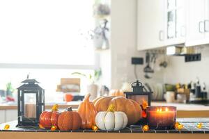 Decor of white classic kitchen with pumpkins, garlands, latern for Halloween and harvest with figurine of house. Autumn mood in home interior, modern loft style. real estate, insurance, mortgage photo