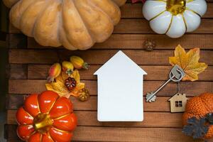 Cozy layout home mock up on a wooden background of slats with pumpkins, autumn leaves, a house and keys - autumn mood, Halloween, housing, relocation, mortgage, insurance. photo