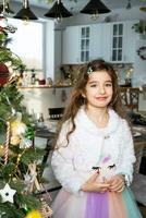 retrato contento niña niño con largo pelo en un hermosa vestir en un hogar interior con un Navidad árbol y nuevo año decoración. preparación para el vacaciones, fiesta foto