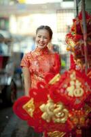 asiático mujer vistiendo chino tradicion ropa con chino bambú ventilador sonriente cara en yaowarat calle China pueblo de Bangkok Tailandia foto