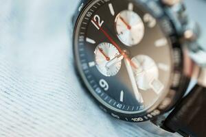 Expensive luxury watches with numbers and chronograph hands lie on jeans fabric, close-up photo