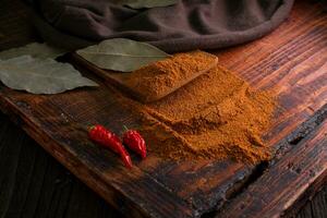Spicy Chili powder seasoning with red dried chili peppers on a wooden background with brown dark color photo