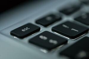 Modern computer keyboard with backlit and focus on the esc button, macro photo