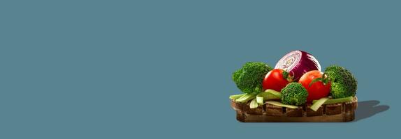 Healthy vegetables on round wooden board isolated on gray background. Photo with copy space.