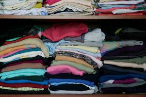 Shelves with complex multicolored clothes. The concept of second hand. photo