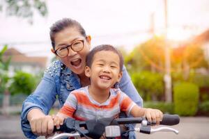 retrato de asiático niños montando bicicleta con madre sonriente cara felicidad emoción foto