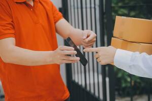 Asian Woman Receiving Product from delivery man at Home, Young Owner Woman Order Product from Smartphone Application, Woman with Online Business or SME Concept. photo