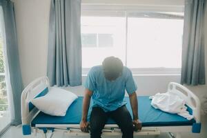 Deprimido mayor hombre sentado en el hospital cama solo a noche, él siente solitario y abandonado foto