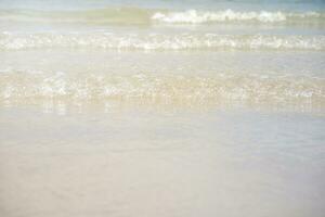 Clear water of waves on sandy beach and light of sun photo