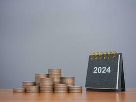 2024 escritorio calendario con apilar de monedas el concepto de ahorro dinero, financiero, inversión y negocio creciente en nuevo año 2024. foto