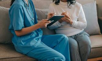 Asian doctor woman visited patient woman to diagnosis and check up health at home or private hospital. Female patient explain health problem and symptoms to doctor .Health care premium service at home photo