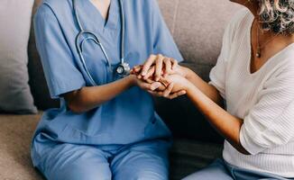 Happy senior woman visiting doctor, getting optimistic news after medical checkup, therapy. Therapist holding hand of old patient, giving hope, support, congratulating on goor treatment result photo