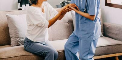 Happy young female nurse provide care medical service help support smiling old grandma at homecare medical visit, lady carer doctor give empathy encourage retired patient sit on sofa at home hospital photo