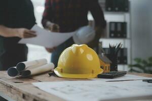 Close up of civil male engineer asian working on blueprint architectural project at construction site at desk in office. photo