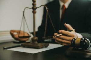 Justice and Law concept. Legal counsel presents to the client a signed contract with gavel and legal law or legal having team meeting at law firm in background photo