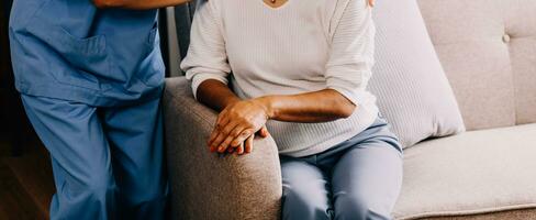 Happy young female nurse provide care medical service help support smiling old grandma at homecare medical visit, lady carer doctor give empathy encourage retired patient sit on sofa at home hospital photo