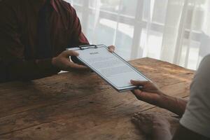 Close up view of job interview in office, focus on resume writing tips, employer reviewing good cv of prepared skilled applicant, recruiter considering application, hr manager making hiring decision photo