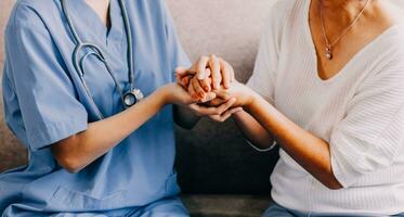 Happy senior woman visiting doctor, getting optimistic news after medical checkup, therapy. Therapist holding hand of old patient, giving hope, support, congratulating on goor treatment result photo