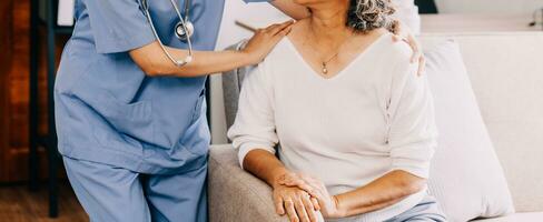 Happy young female nurse provide care medical service help support smiling old grandma at homecare medical visit, lady carer doctor give empathy encourage retired patient sit on sofa at home hospital photo