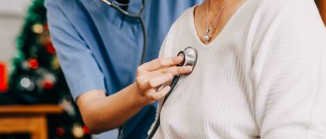 Lady coming to clinic for heart and lungs checkup, male doctor using stethoscope, listening to female patient's breath or heartbeat, sitting in clinic office photo