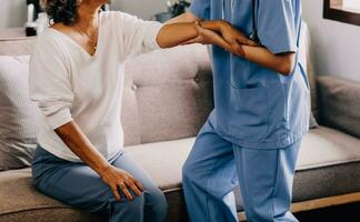 contento joven hembra enfermero proporcionar cuidado médico Servicio ayuda apoyo sonriente antiguo abuela a cuidados en el hogar médico visita, dama cuidador médico dar empatía animar retirado paciente sentar en sofá a hogar hospital foto