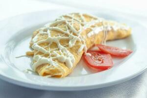 Rolled egg omelets filled with chicken garnished with mayonnaise and sliced tomatoes photo