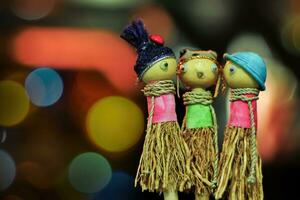 Three children's toy dolls made of wood and straw on a blurred background photo