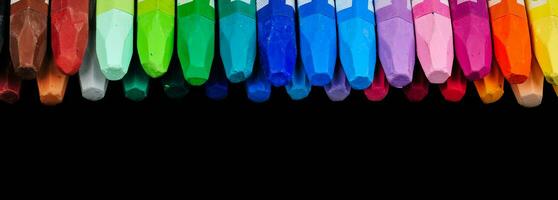 un colección de pulcramente arreglado lápiz de color palos visible desde encima en un fila de vistoso colores foto