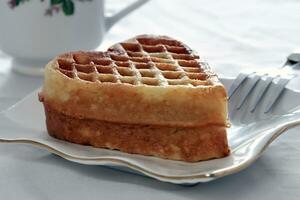 Heartshaped waffles are served on a plate with a cup of tea photo