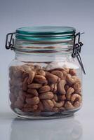 a bunch of cashews in a glass jar with a green lid on a white isolated background photo