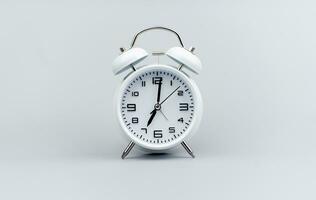 White alarm clock on gray background, time standing still Importance of time and work, punctuality, value of time photo